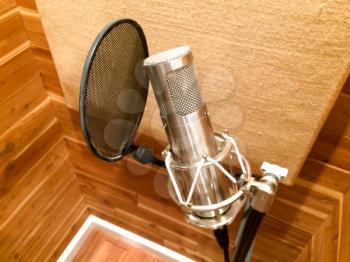 Professional microphone in music recording studio booth with pop wind filter