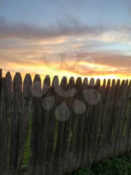 sunset green grass rustic wooden fence with yellow blue gold colors and tree