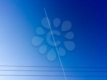Electric power lines with jet stream and blue sky
