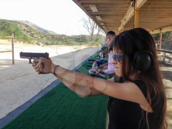 shooting range outdoor with cute girl holding self defense handgun firearm aiming target