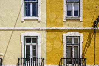 Bright yellow facade  with square symmetrical windows in Lisbon, Portugal