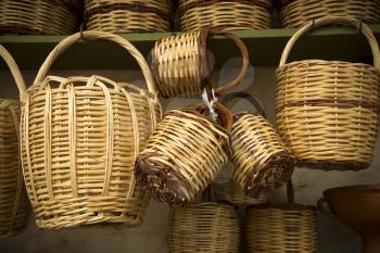 Straw baskets on sale hang on a wall in a market