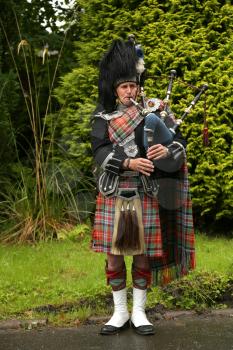 EDINBURGH, SCOTLAND - JULY 28 2015 : Unidentified Scottish Bagpiper playing music with bagpipe in Scotland.  Bagpipes are a class of musical instrument, aerophones, and have been played for centuries.