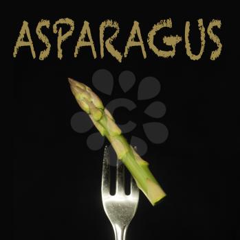Asparagus on a fork on a black background