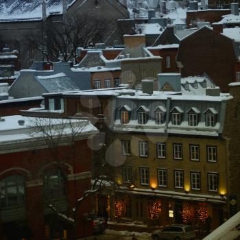 View of the roofs and windows of old buildings in Quebec during winter at dusk
