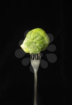 Brussels sprout on a fork on a black background