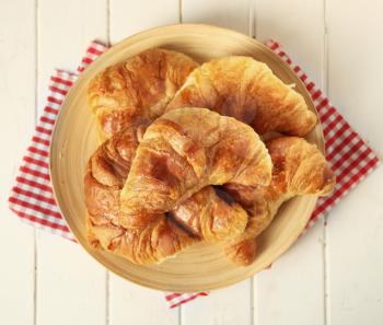 Fresh homemade croissant in a plate on a wooden background