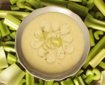 Top view of a celery soup surrounded with fresh vegetables