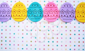 Decorated felt easter eggs yellow, pink, blue and lilac on a 
 polka dots background