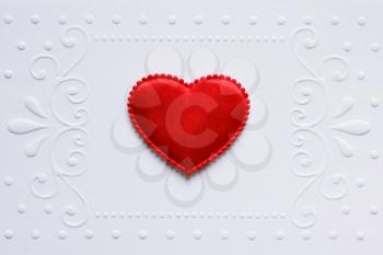 Blank embossed white paper with red satin hearts on it.  