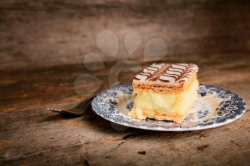 Millefeuille, french pastry with custard in a blue plate and wooden table