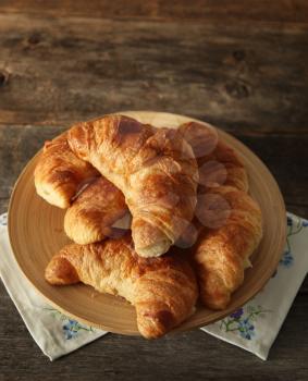 Fresh homemade croissant in a plate on a wooden background