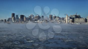 Montreal by a very cold day.  St-Lawrence river with steam on it with downtown Montreal in background in Quebec province in Canada