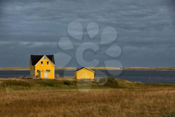 Beautiful yellow house by the sea.  Rugged cost line of Havre Aubert in magdalen island in Quebec, Canada