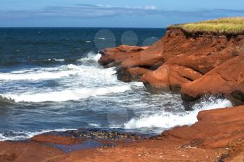Red cliff in Cap aux Meules with waves in the ocean in the St-Lawrence golfe in iles de la madeleine in Canada