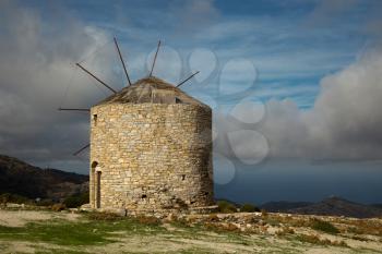Beautiful view of a windmill on the top of a hill with a view on the ocean by a nice summer day in Naxos, Greece