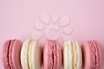 Row of traditional french macarons on pink background