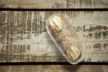 Cannoli in a paper on a grunge wooden background