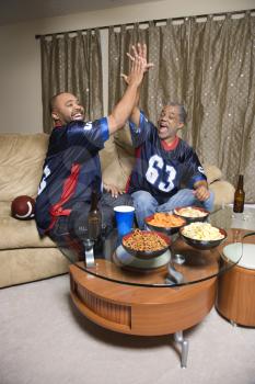 Royalty Free Photo of a Father and Son Giving High Fives While Watching a Football Game