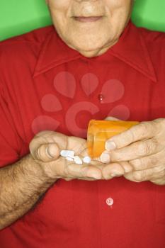 Royalty Free Photo of a Man Emptying a Pill Bottle into Hand