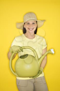 Royalty Free Photo of a Young Female Holding a Watering Can While Wearing a Straw Hat