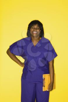 African-American  mid-adult woman in medical uniform smiling holding chart.