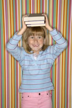 Royalty Free Photo of a Little Girl Balancing Books on Her Head