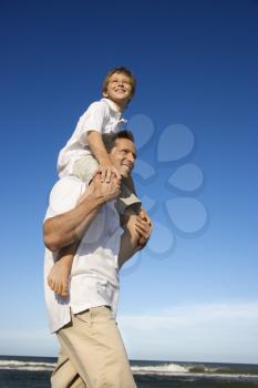 Royalty Free Photo of a Father With a Preteen on His Shoulders on a Beach