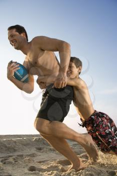 Royalty Free Photo of a Father Running With a Football Being Tackled by His Son