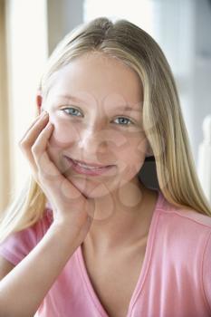 Royalty Free Photo of a Preteen Girl Resting Chin in Hand and Smiling