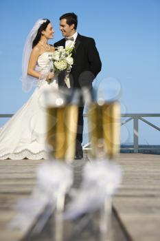 Royalty Free Photo of a Pair of Flute Glasses of Champagne With a Bride and Groom in the Background