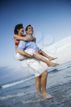 Royalty Free Photo of a Man Giving a Woman a Piggyback on the Beach