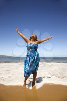 Royalty Free Photo of a Woman Standing on the Beach With Her Arms Up