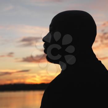 Royalty Free Photo of an African-American Man Standing by Water at a Sunset in Washington, DC, USA.