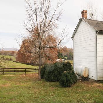 Royalty Free Photo of a House in a Rural Setting in Autumn With a Standing Oil Tank Outside