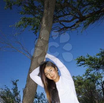 Royalty Free Photo of a Female Holding a Tree and Looking at Viewer