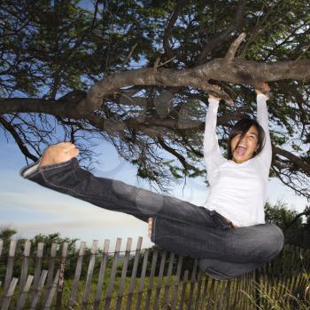 Royalty Free Photo of a Woman Holding on to Tree and Kicking and Screaming