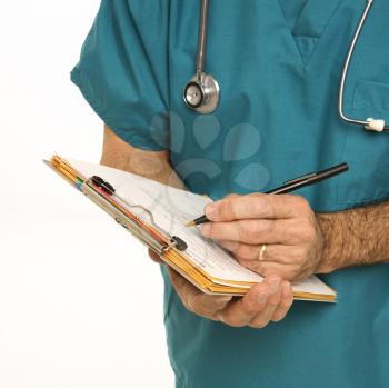Royalty Free Photo of a Male Doctor in Scrubs Making Notes on a Patient's Chart