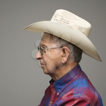 Profile portrait of elderly man wearing plaid shirt and cowboy hat.