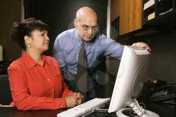 Royalty Free Photo of a Businessman and Businesswoman in an Office Looking at a Computer Monitor