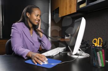 Royalty Free Photo of a Young Businesswoman Working on a Computer in an Office Smiling