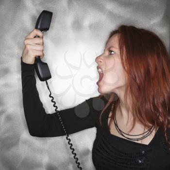 Royalty Free Photo of a Redheaded Woman Yelling into a Telephone Receiver 