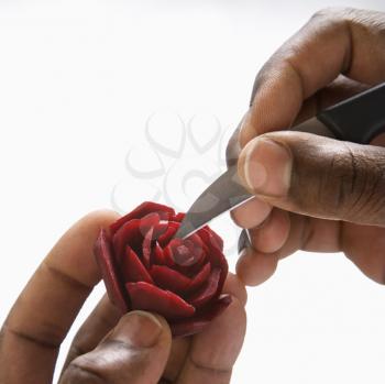 Royalty Free Photo of a Man Carving a Beet into a Rose