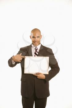African American man holding and pointing to blank sign standing against white background.