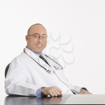 Caucasian mid adult male physician sitting at desk smiling.