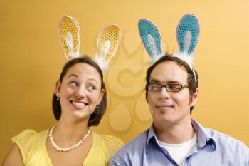Royalty Free Photo of a Couple Wearing Rabbit Ears and Looking at Each Other