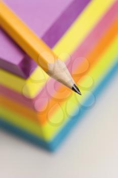 Close up of sharp pencil on stack of colorful sticky notes.