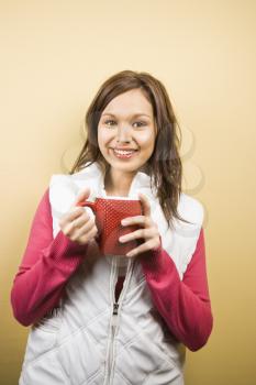 Royalty Free Photo of a Young Woman Holding a Coffee Cup and Smiling