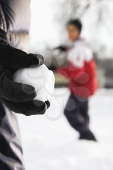Royalty Free Photo of a Boy Holding a Snowball Ready to Throw it at a Boy in the Background