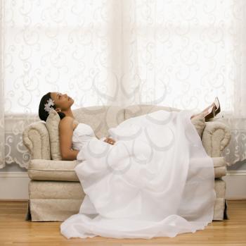 Royalty Free Photo of a Bride Lying on a Love Seat